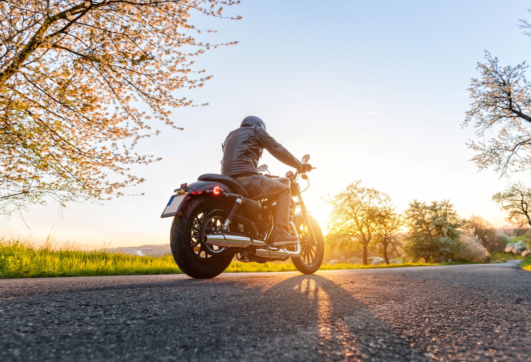 Prise de vue en contre-plongée d'une moto sur la chaussée au coucher du soleil